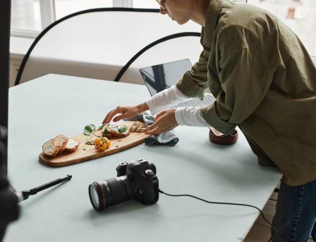 Cropped shot of female food photographer setting up gourmet bruschetta with props in studio, copy space